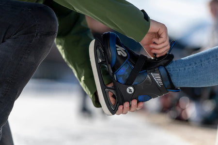 Vater zieht Kind Schlittschuh an